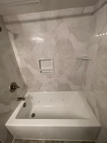 White bathtub with marble-like wall panels.