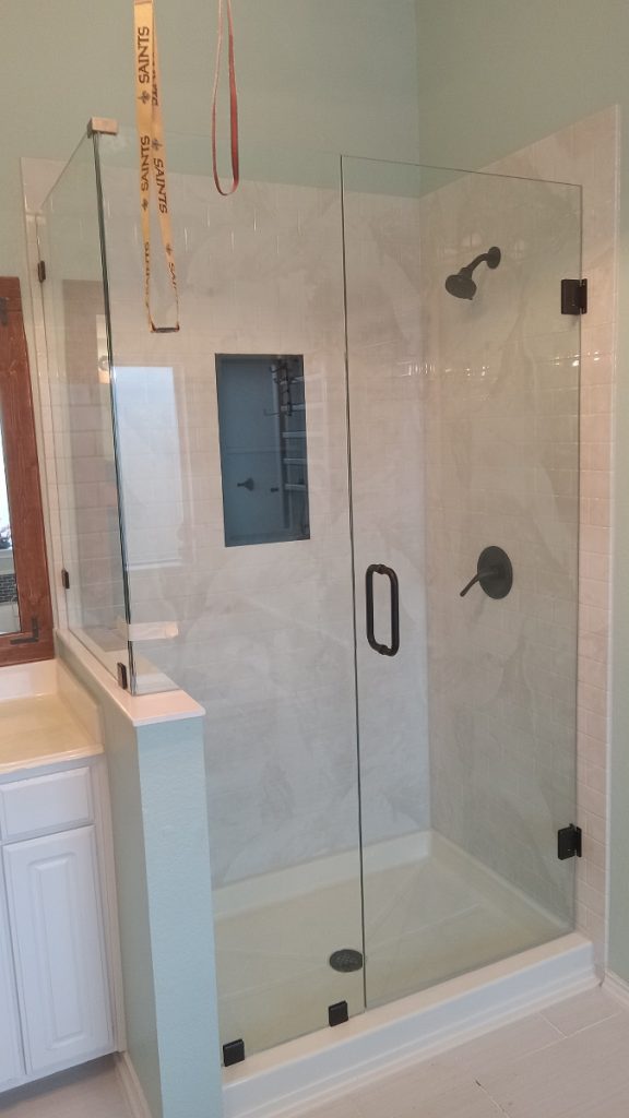 Frameless glass shower door with black hardware.