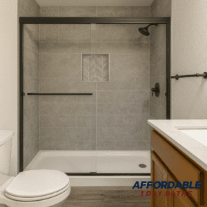 A modern tub-to-shower conversion in a Denton, TX home featuring gray tile walls, a herringbone accent niche, and black-framed glass doors by Affordable 1 Day Baths