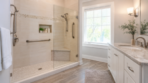 Bright bathroom with low-threshold walk-in shower, grab bars, built-in bench, handheld showerhead, and neutral finishes.
