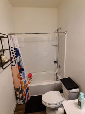 Bathroom with a toilet, sink, bathtub, and shower curtain.
